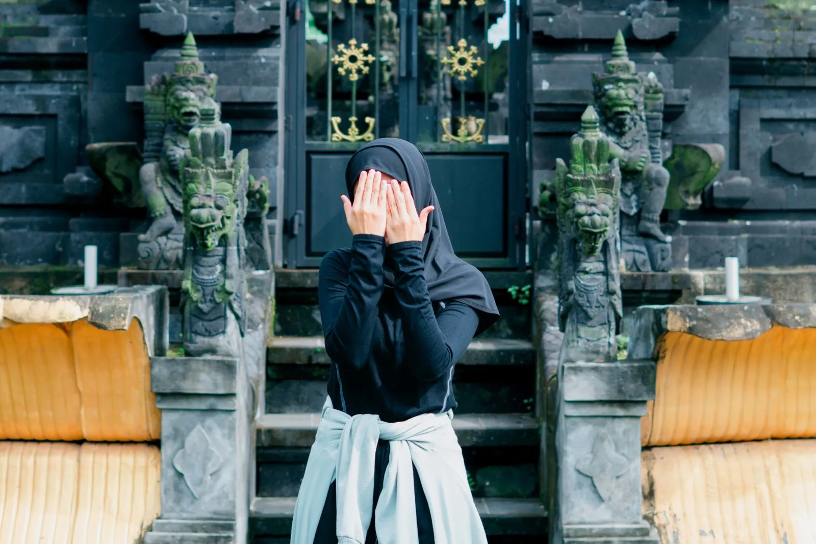 A woman in a black outfit poses mysteriously at a traditional temple in Banten, Indonesia.